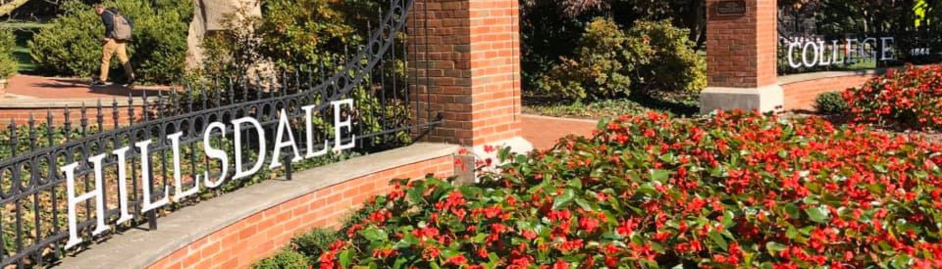 The entrance to Hillsdale College, surrounded by colorful flowers and lush greenery.