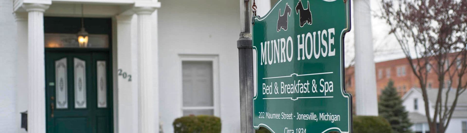 Sign for Munro House Bed & Breakfast and Spa outside a white house in Jonesville, Michigan.