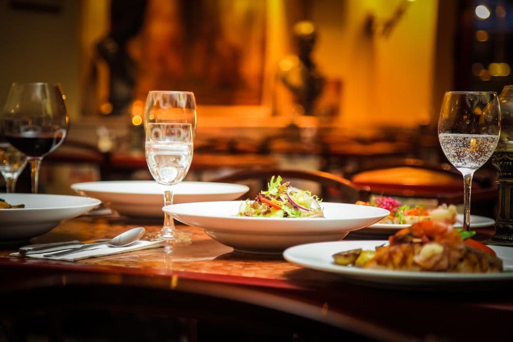 A beautifully set dining table with assorted dishes and glasses of wine and water.
