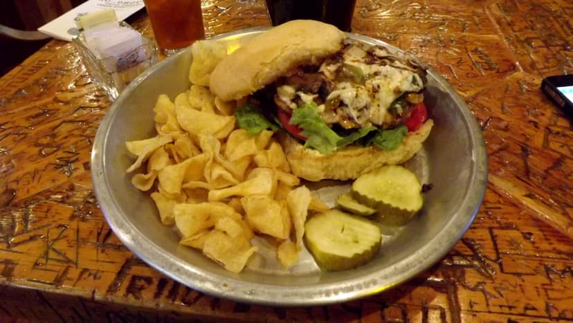 sandwich with chips on a tin plate with graffiti carved table