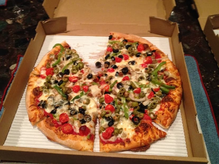 open pizza box with veggie pizza missing one slice