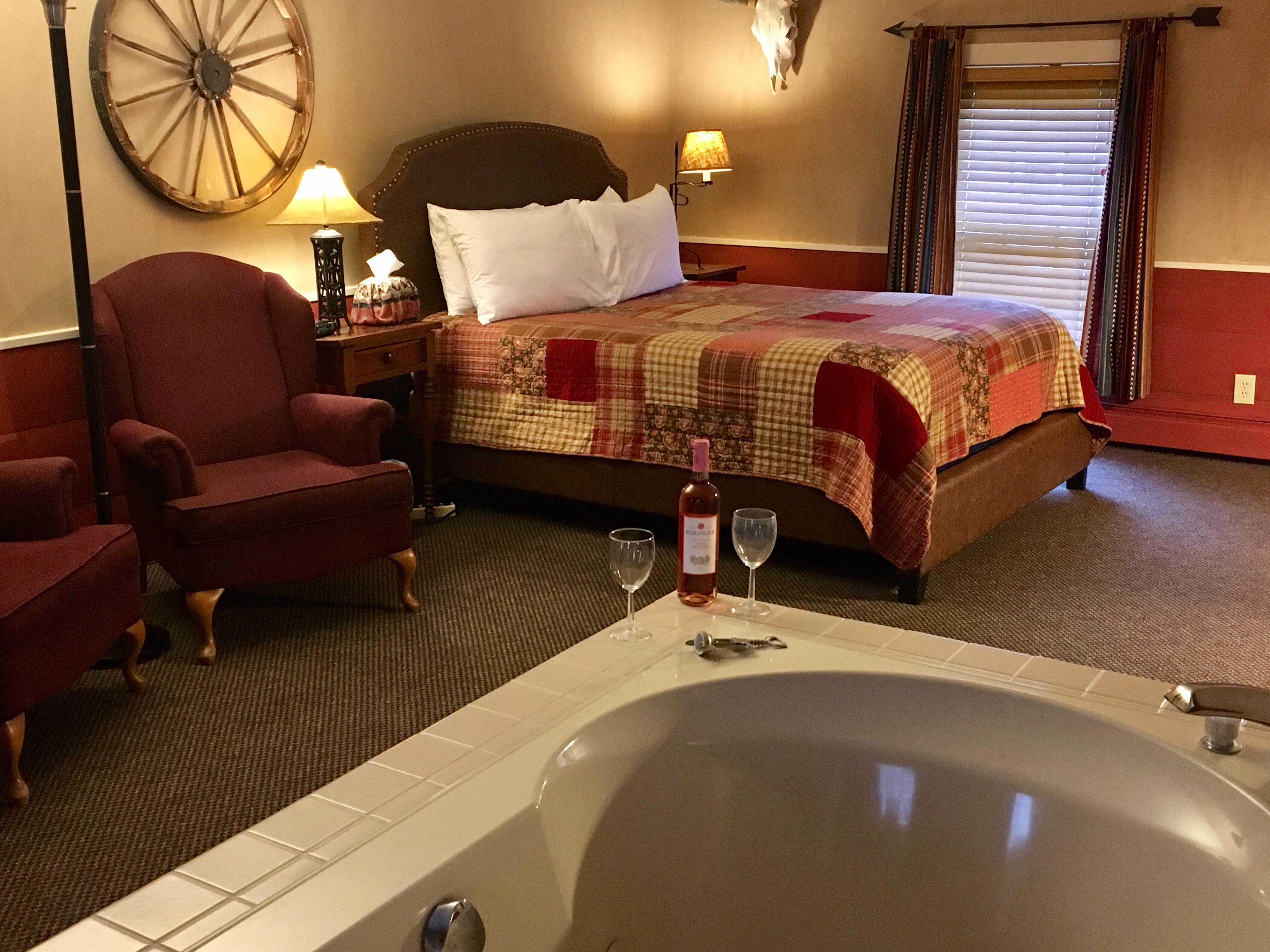 Rustic bedroom with wagon wheel, jacuzzi tub, and wine