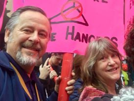 mike venturini and lori venturini, man and woman carrying pink sign in a protest march
