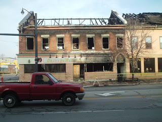 red pickup truck passing by a burned out building