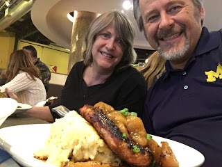 woman in black and man in blue enjoying pork rib eye with fuji apples and mashed potatoes