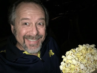movie theater dark theater with man in blue shirt enjoying a large bag of popcorn