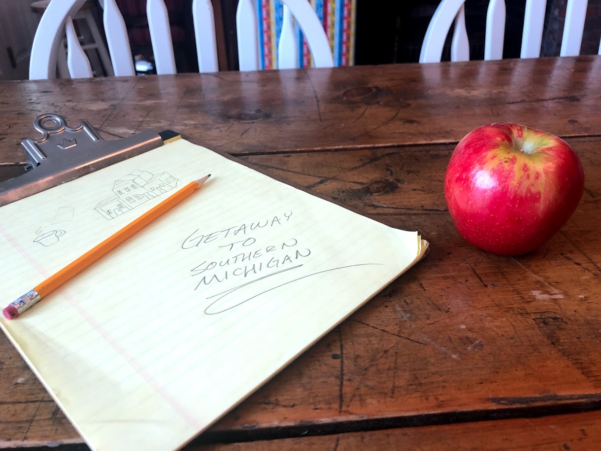 Yellow legal paper with pencil on a clip board with a red apple off to the side