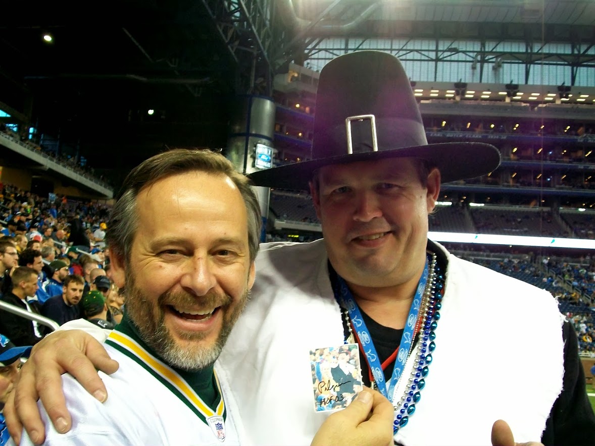 two men at Ford Field in Detroit. one wearing a football jersey, the other in a Pilgrim costume