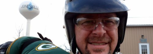 biker wearing helmet and green gloves in front of jonesville water tower