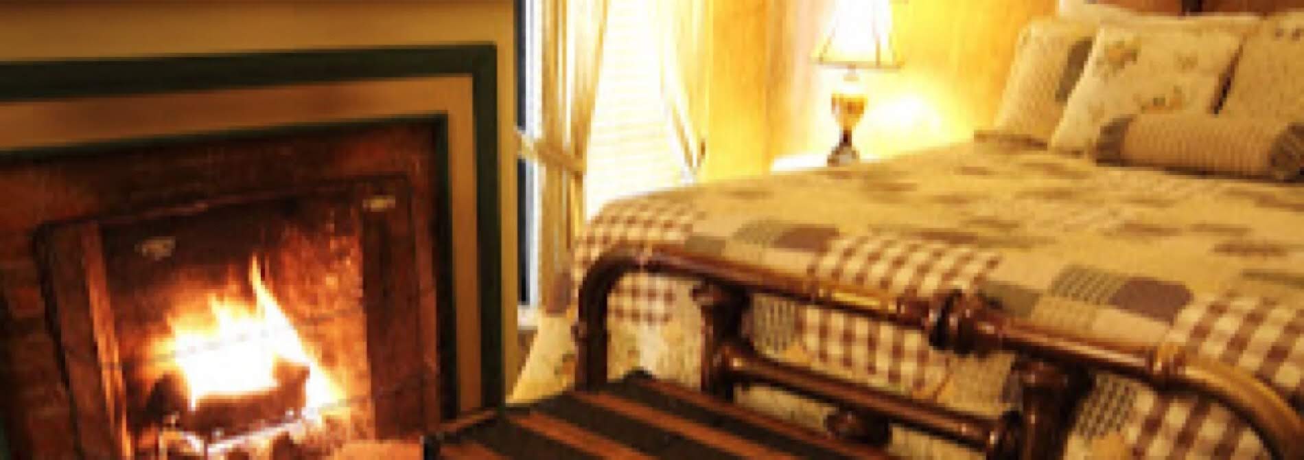 plaid bedspread on brass bed with lit fireplace