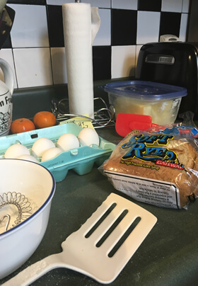 eggs bread and butter on a green counter top with white spatula and paper towel
