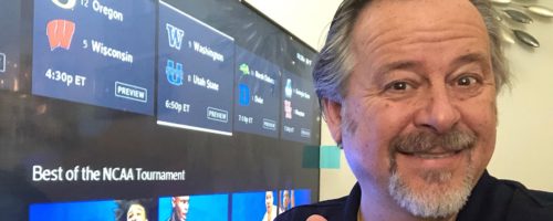 man in front of TV screen with ncaa basketball tournament choices