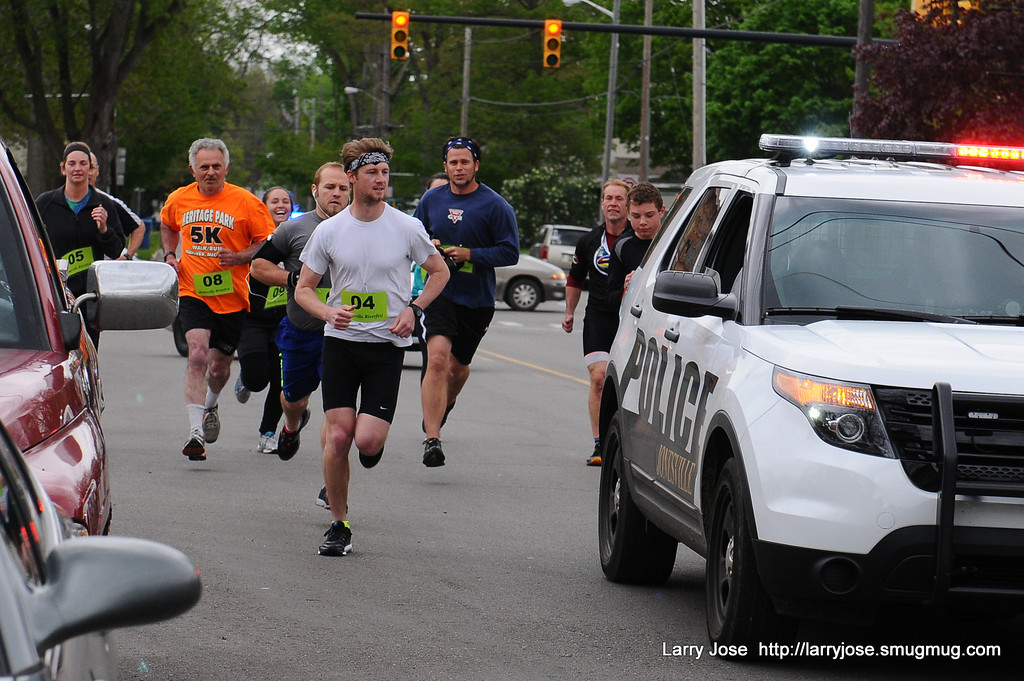 Road race runners escorted by police vehicle