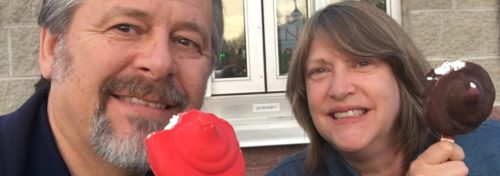 man and woman eating ice cream on a stick one chocolate one cherry